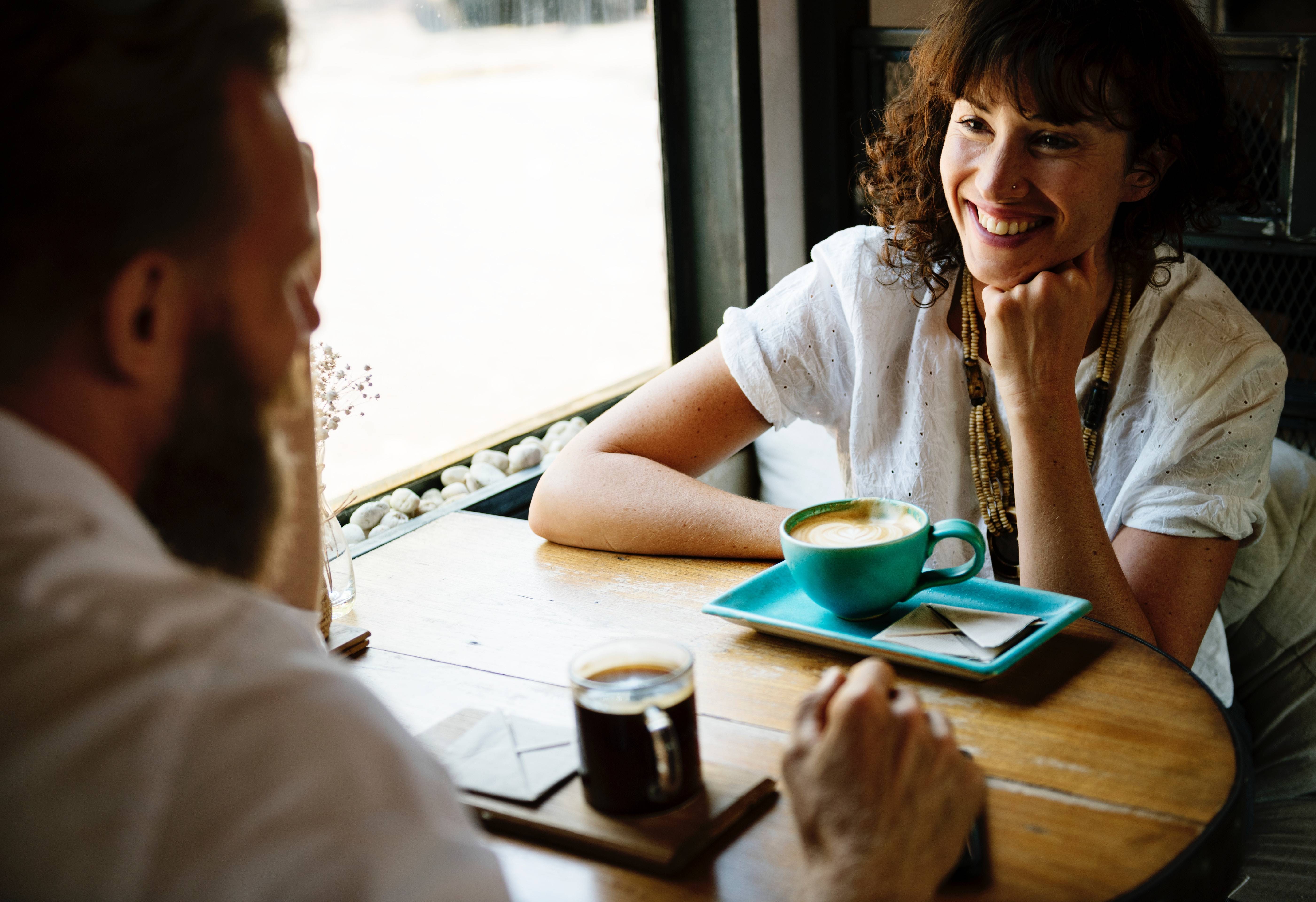 man and woman smiling in a cafe