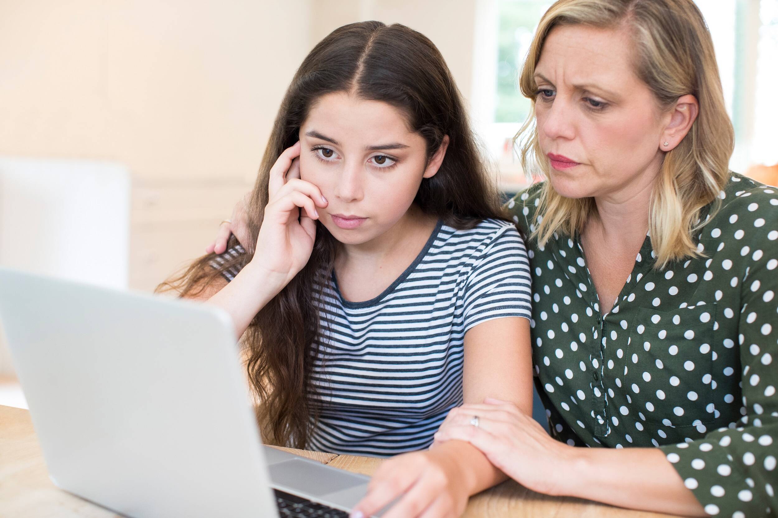 Sad daughter and her mother looking at laptop