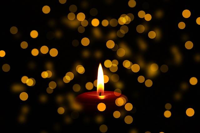 burning candle with blurry lights behind