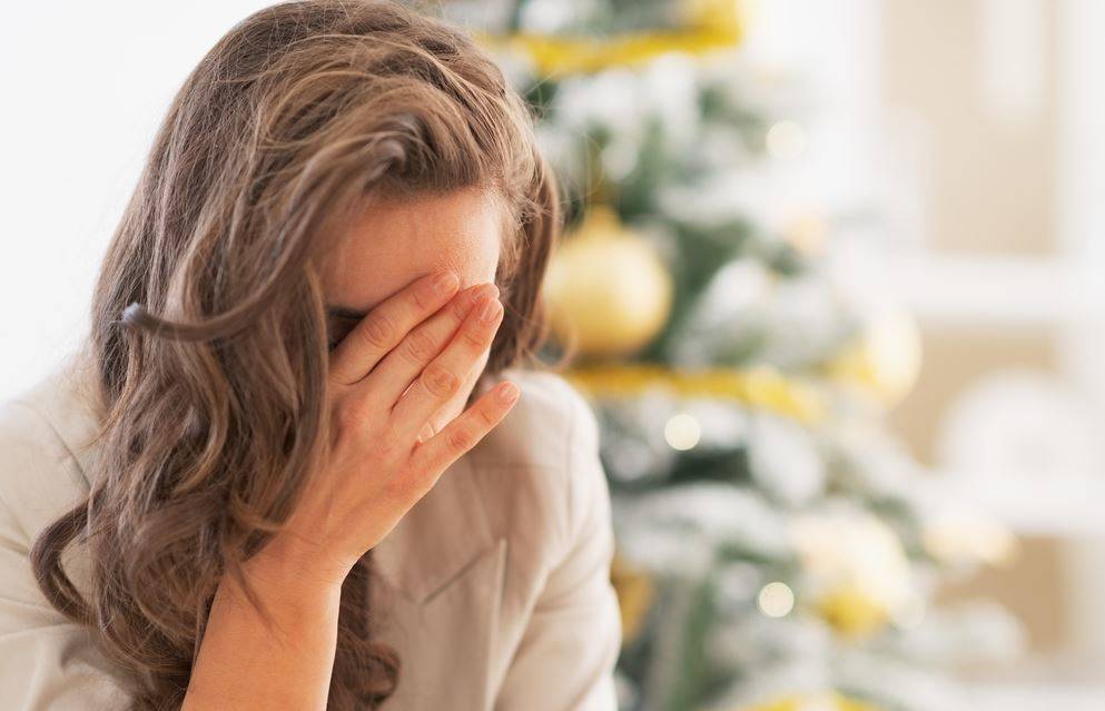 sad woman in front of a christmas tree