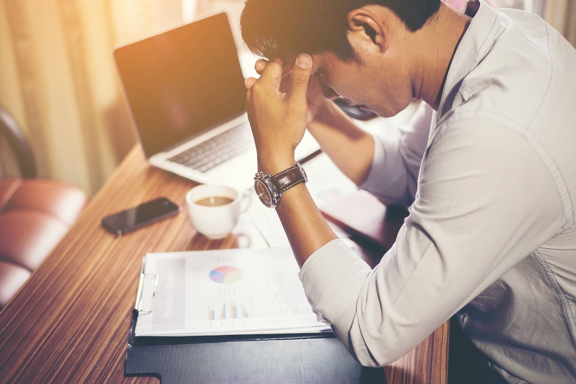 man with head in hands at work desk