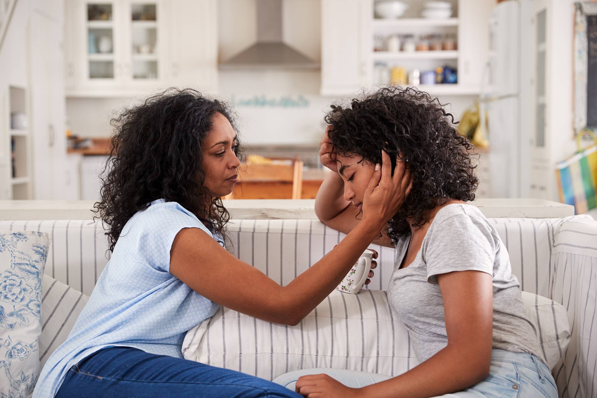 Mother helping teenager with grief on sofa