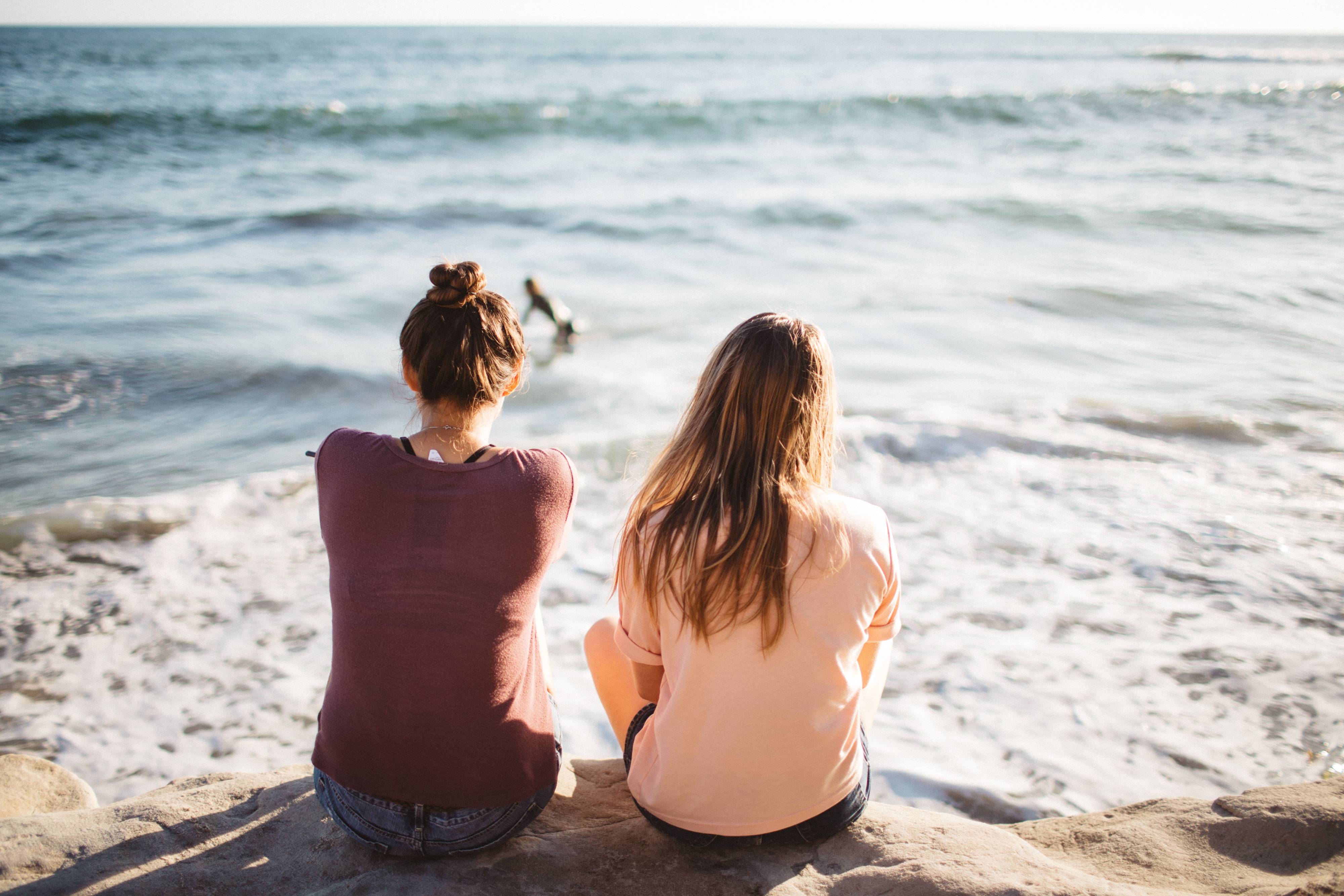 Two women sitting on a beach