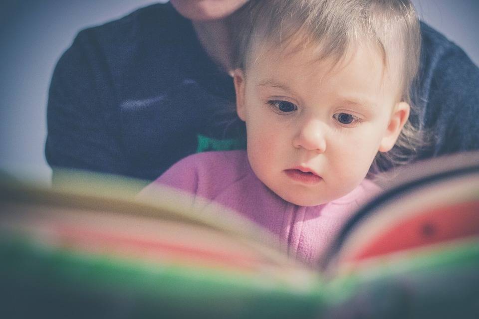 child reading a book with adult