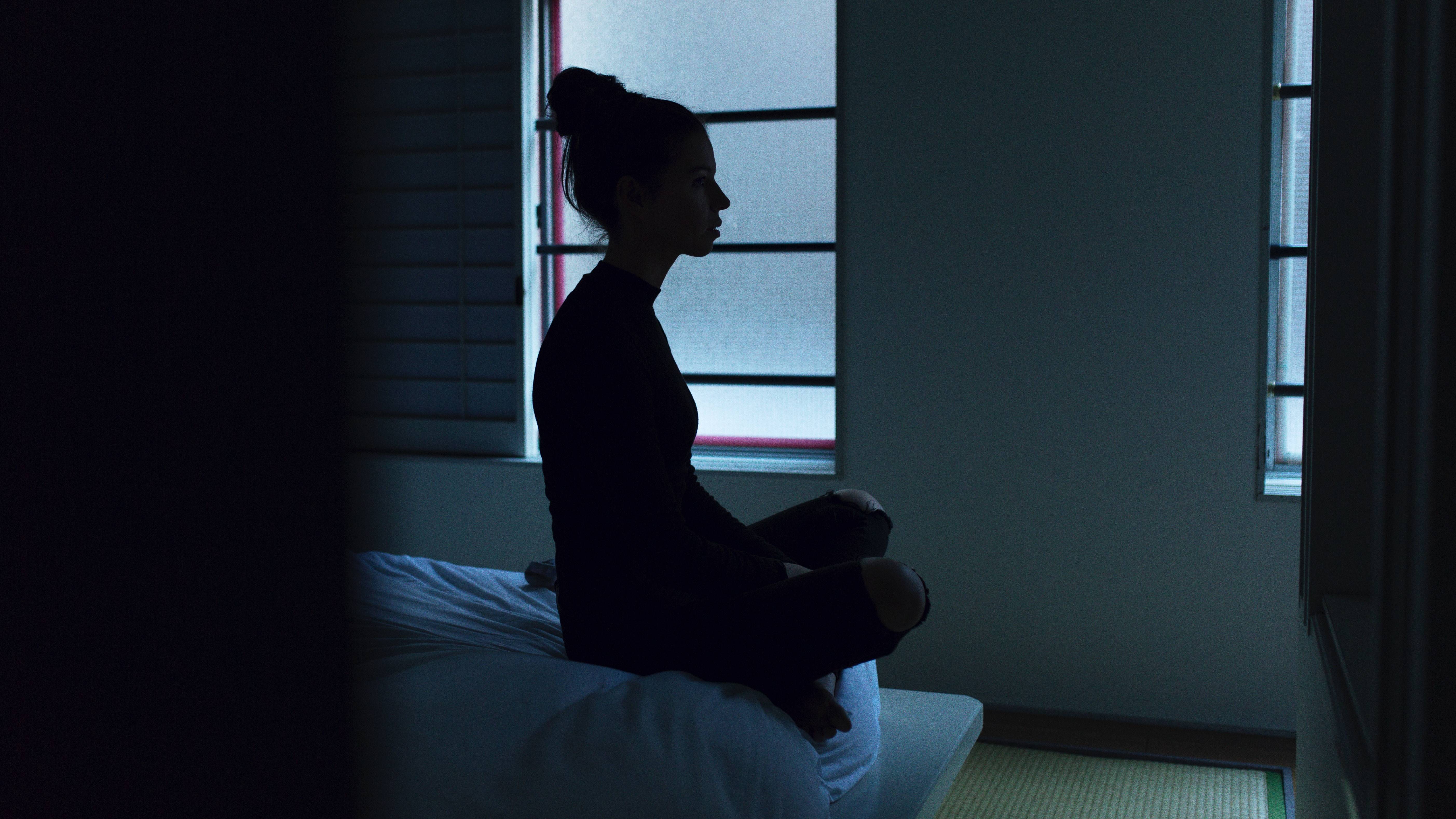 woman sitting on end of bed at night