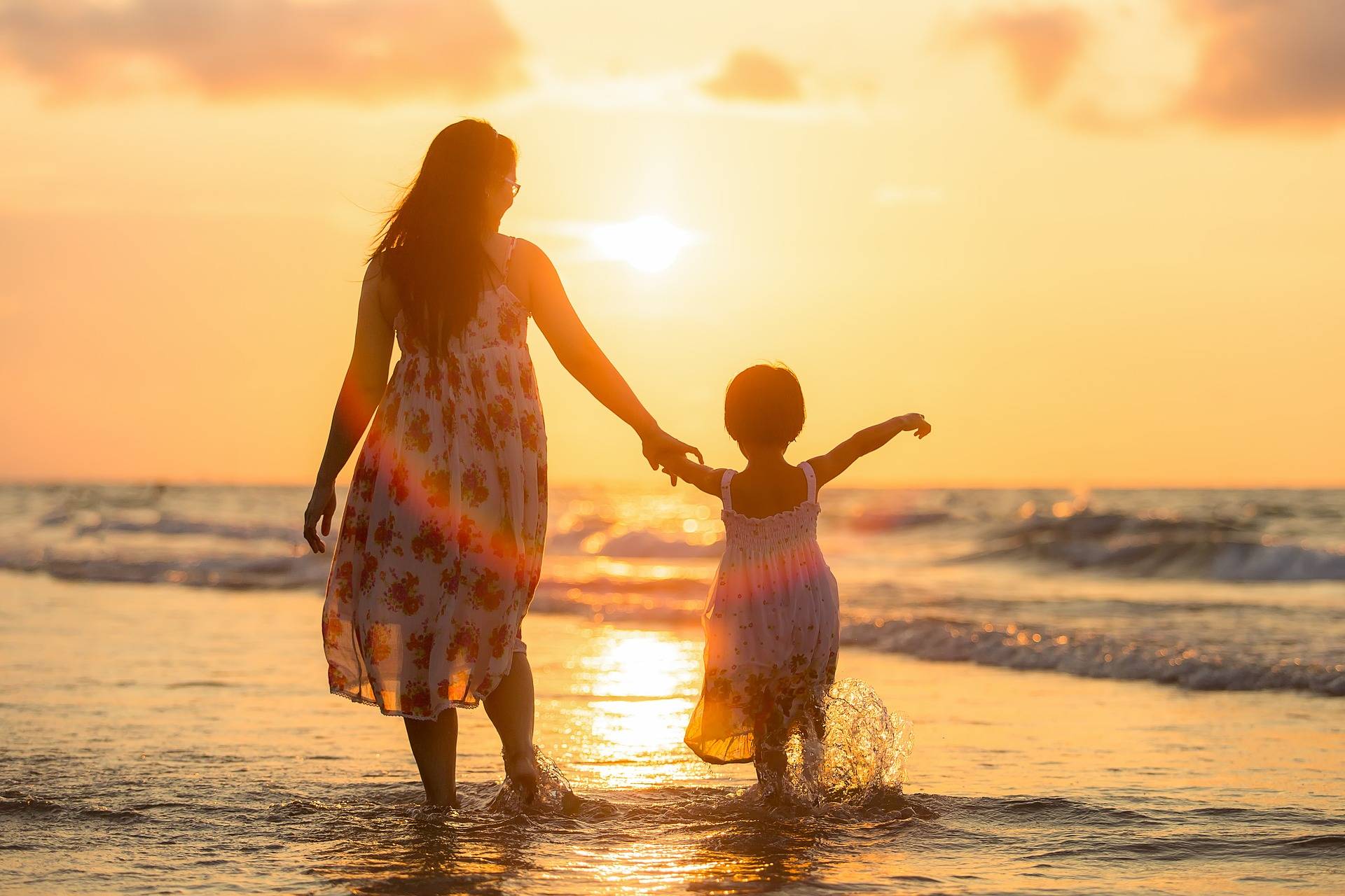 mother and daughter walking along the shore
