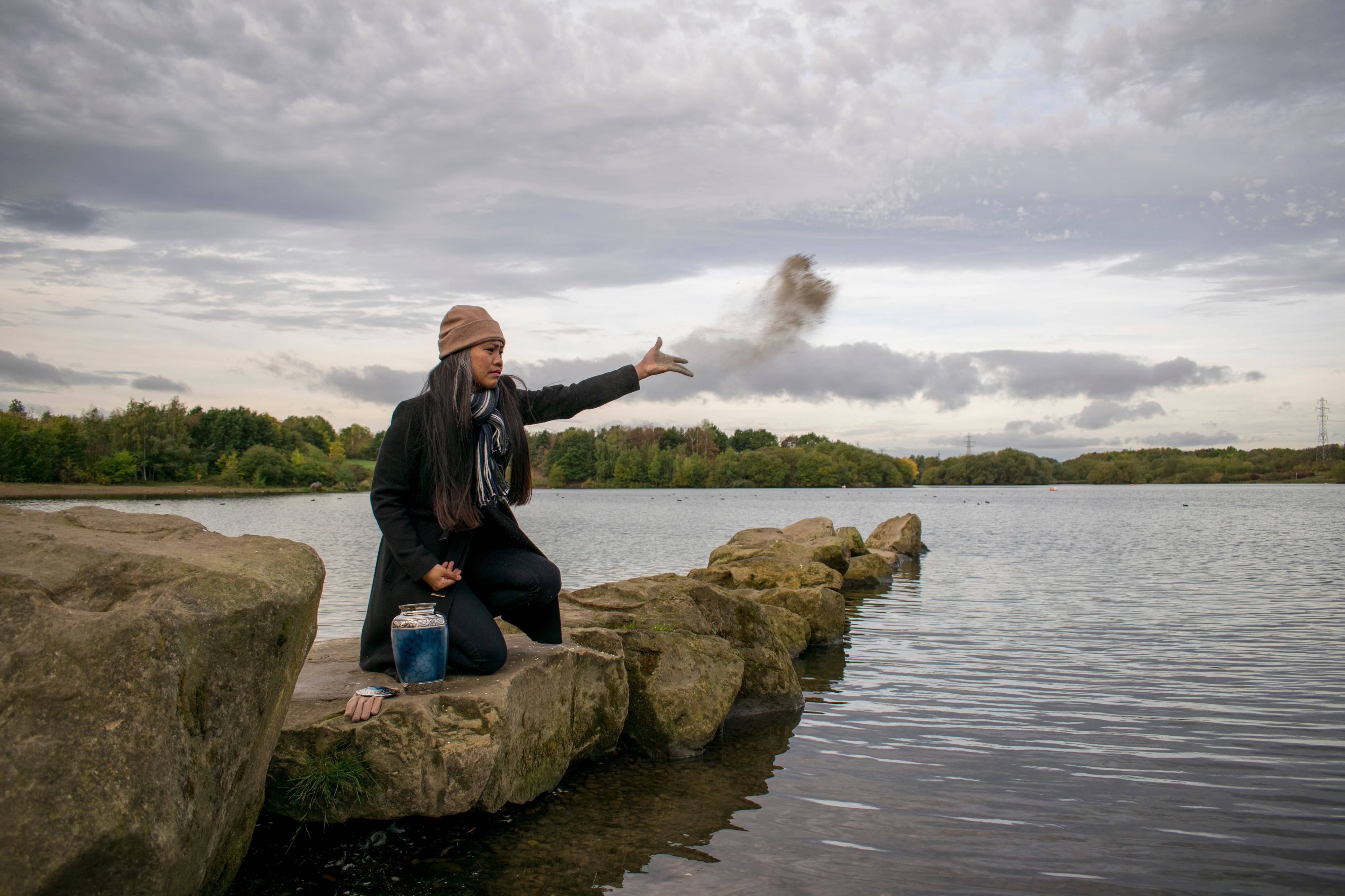 Woman scattering ashes at lake