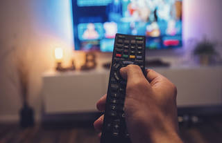 Man pointing remote at television