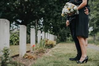Couple looking at headstone with flowers