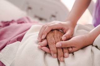 Young person holding hands with older person